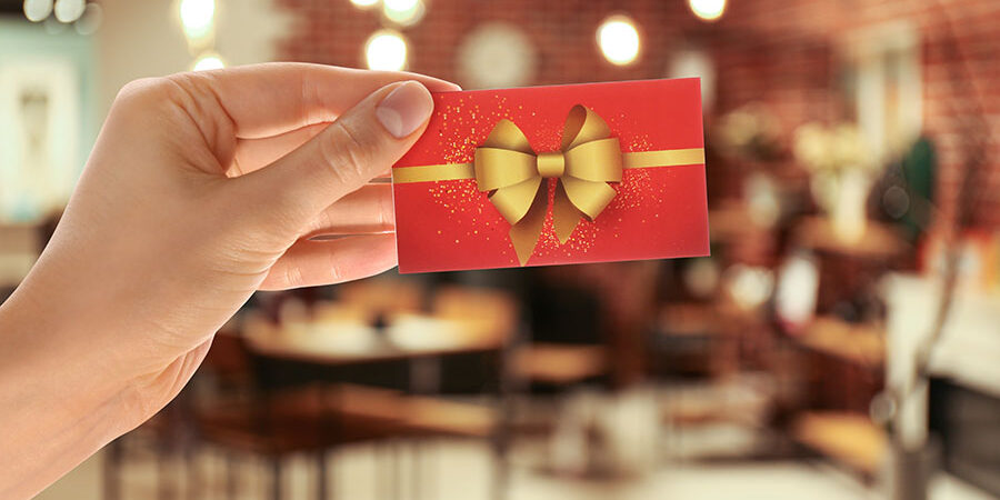 Woman holding gift card in restaurant, closeup Focus eGift