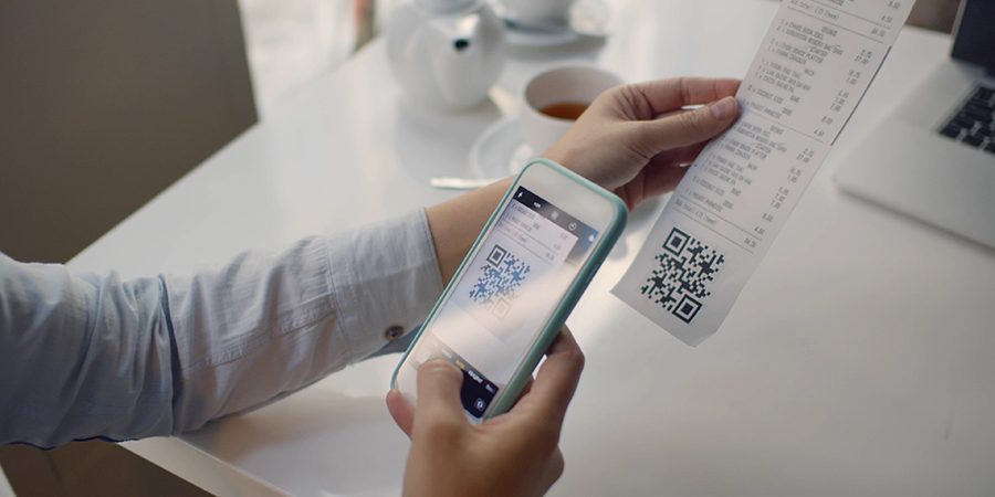 Close up of woman using smartphone and scanning qr code on cash shop receipt Close up of woman using smartphone and scanning qr code on cash shop receipt
