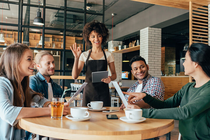 Young African American woman waitress taking orders from clients Young african american woman waitress taking orders from clients in cafe