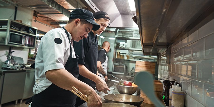 New skills. Two chef assistants cooking a new dish in a restaurant kitchen. Cooking School