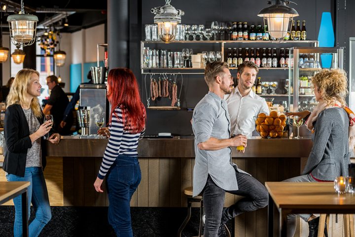Young friends talking while having their drinks at bar counter